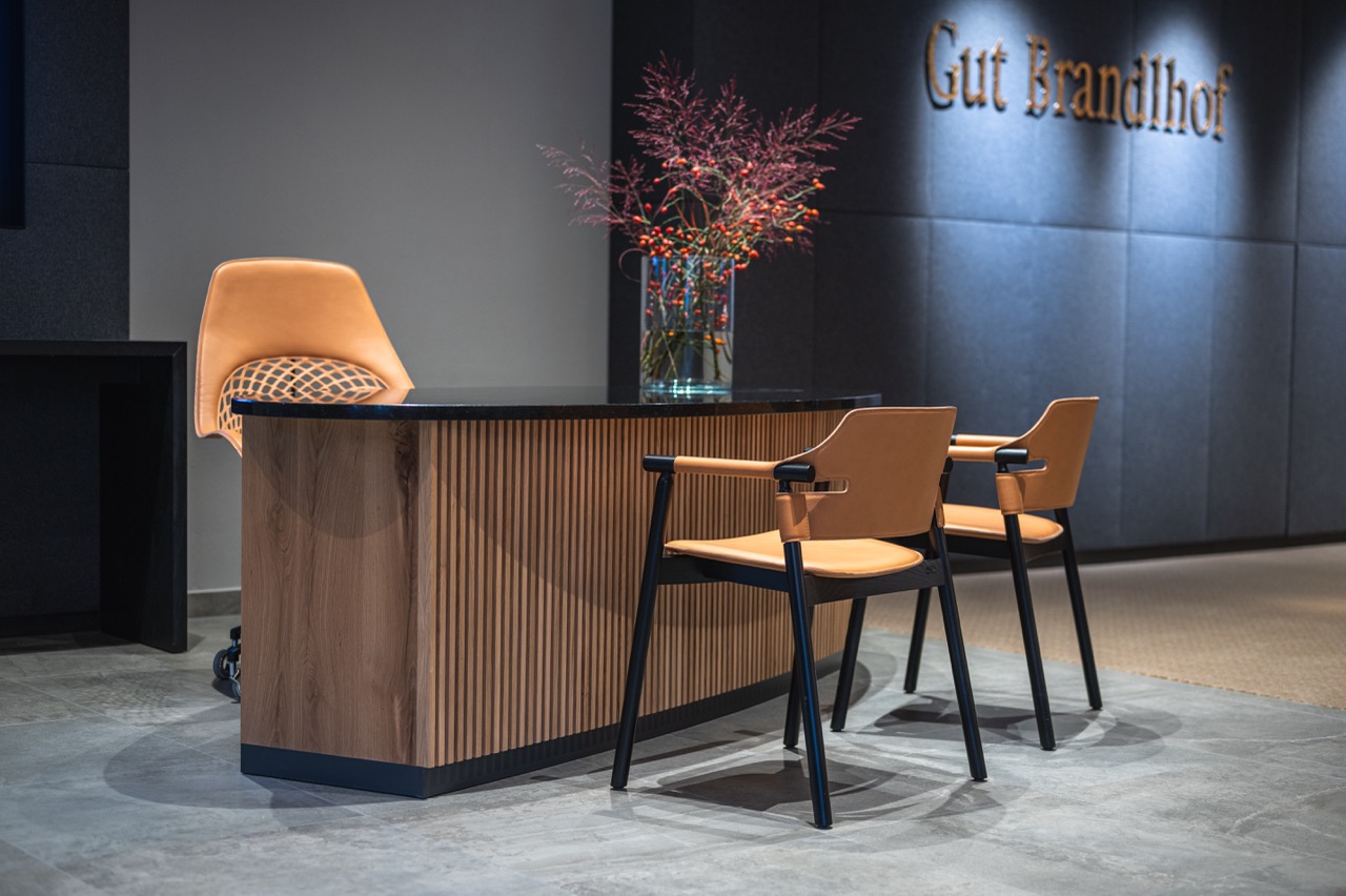 Empfangsbereich des Gut Brandlhof mit Designmöbeln und Blumenarrangement