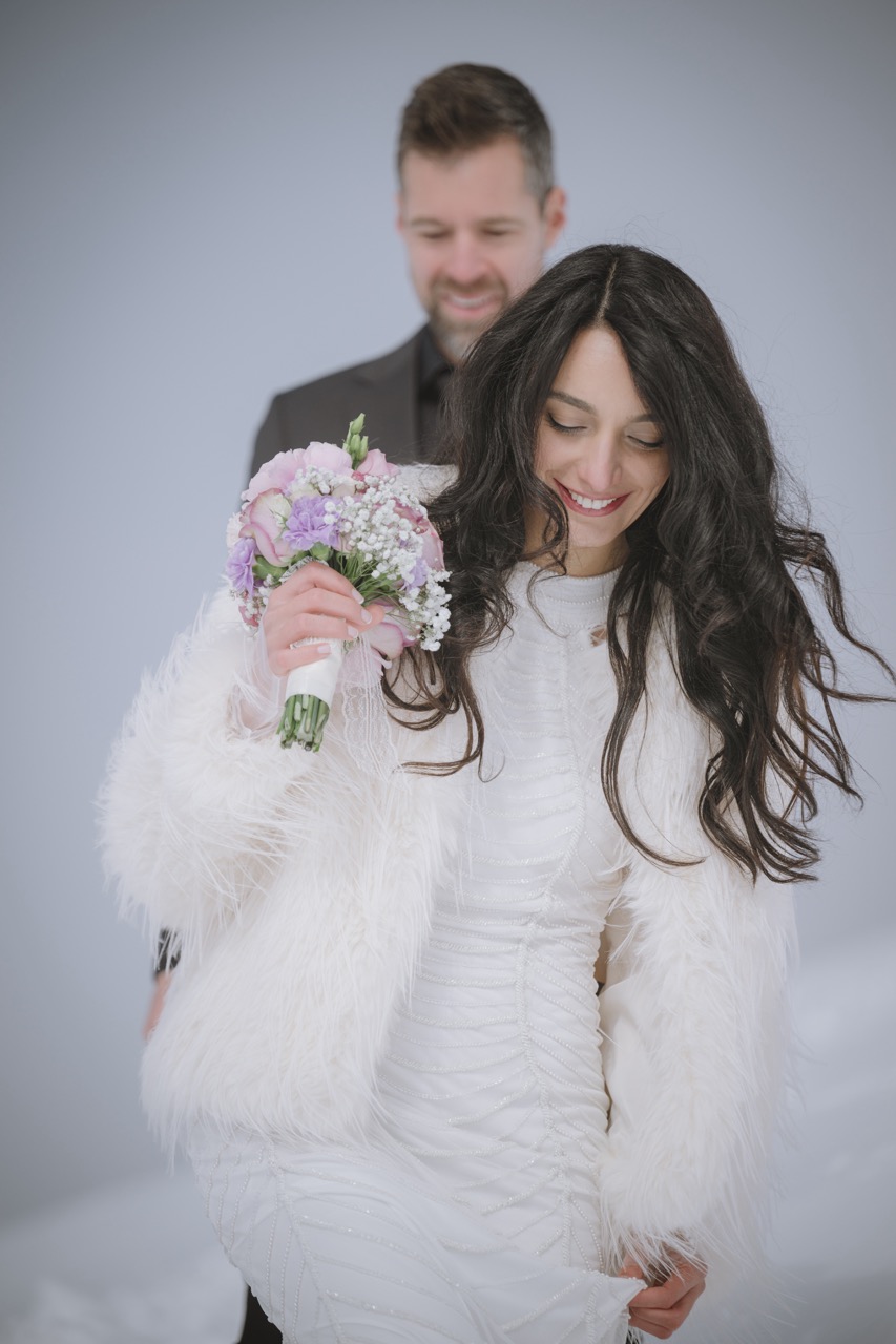 Lachende Braut mit Blumenstrauss in winterlicher Schneelandschaft