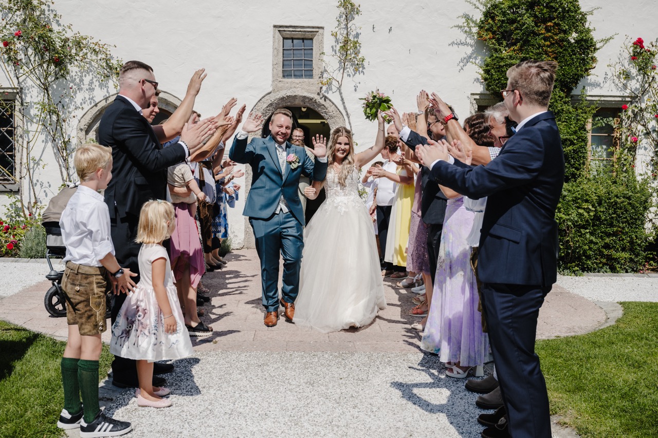 Hochzeitsgesellschaft jubelt dem Brautpaar beim Auszug aus der Kirche zu