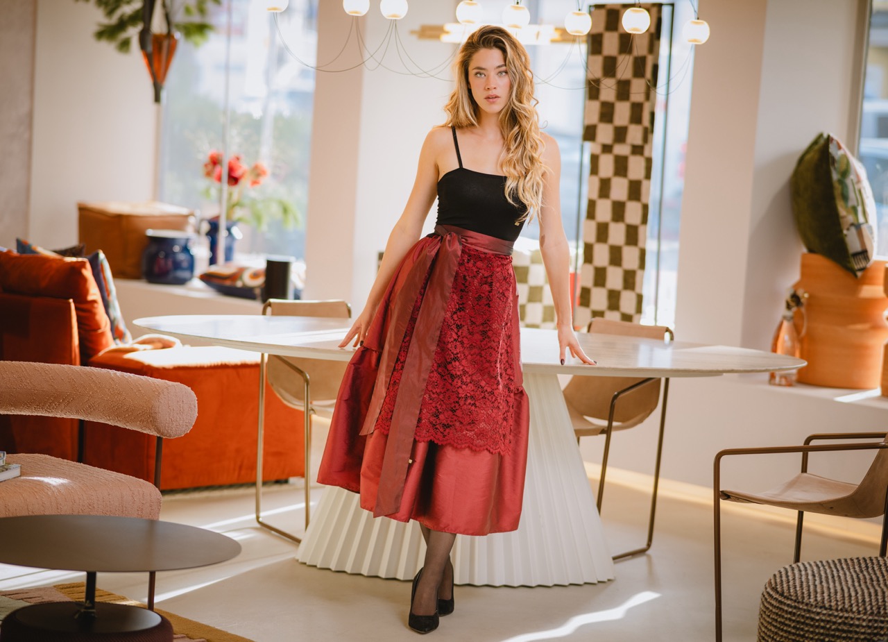 Modeportrait einer Frau im burgunderfarbenen Rock in modernem Interieur